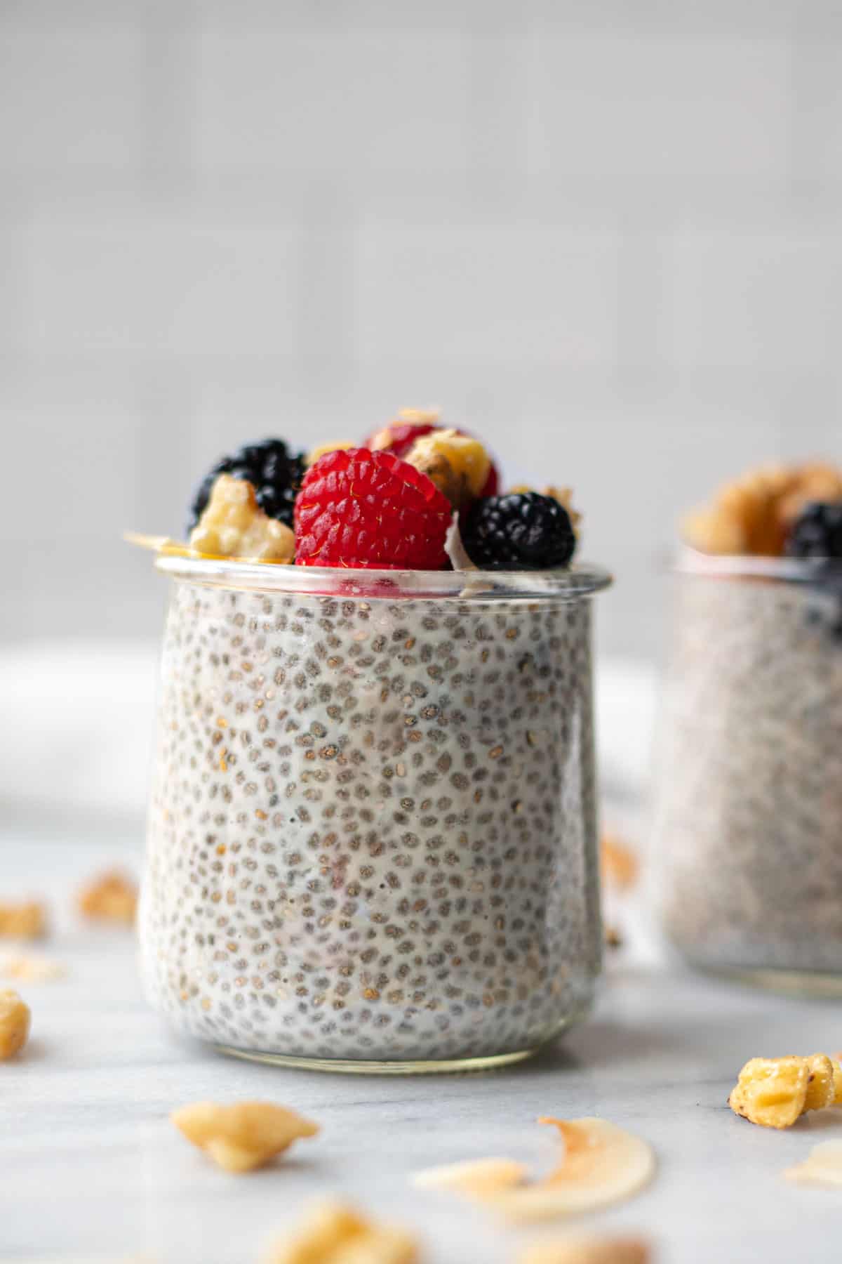 Finished chia pudding in a glass jar topped with berries and nuts.