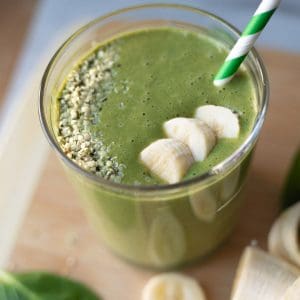 Green smoothie in a glass with a straw coming out