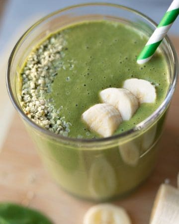 Green smoothie in a glass with a straw coming out