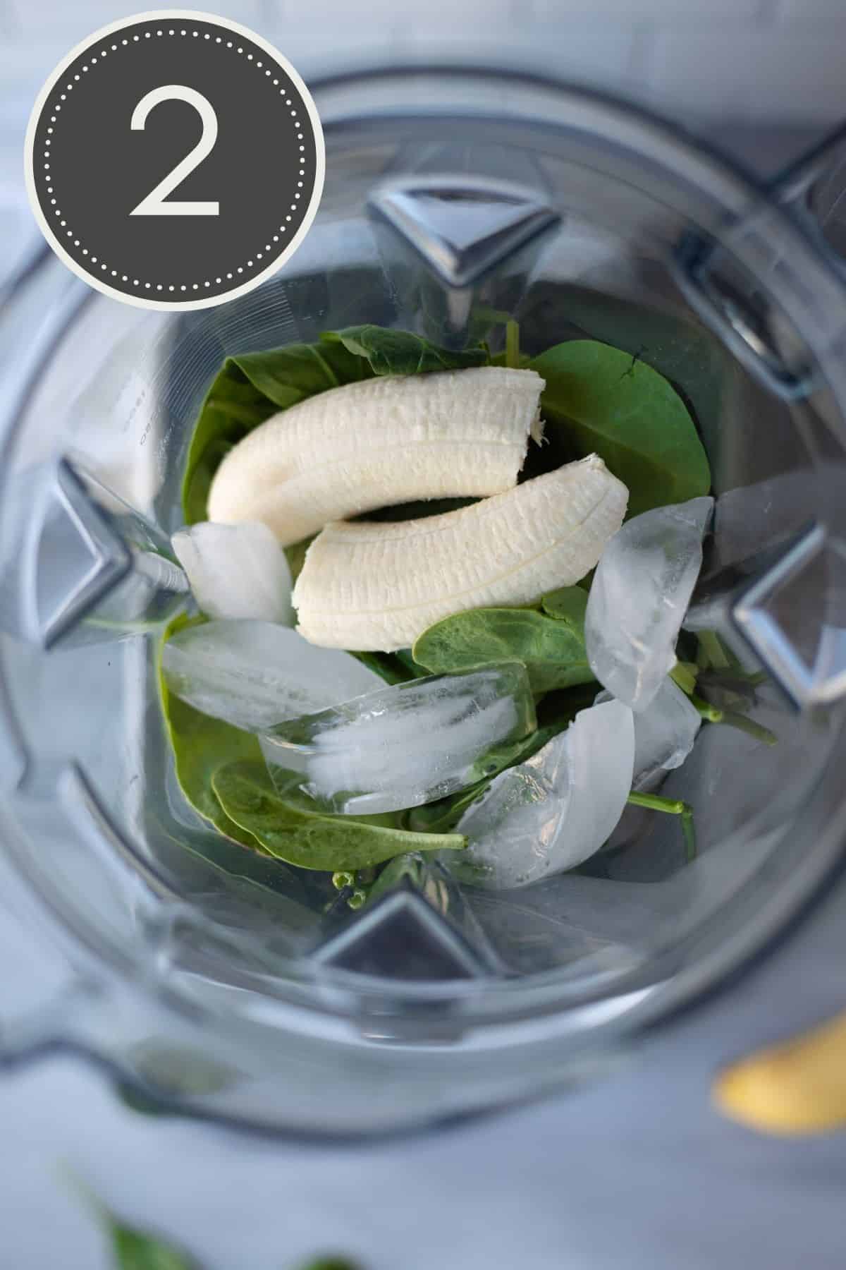 Top down view of a blender filled with frozen bananas, spinach, and ice cubes.